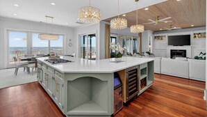 Una cocina moderna con una isla grande, iluminación colgante y vistas al exterior.