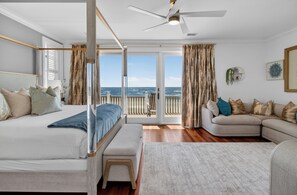 Un dormitorio con cama, un banco, un sofá y un balcón con vista al mar.