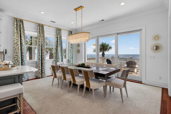 A modern kitchen with a dining area, large windows, and a view of the ocean.