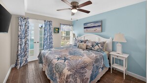 A bedroom with a bed, a ceiling fan, a nightstand, and a window with curtains.