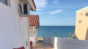 Une terrasse extérieure aménagée avec des meubles en osier et offrant une vue sur la mer.