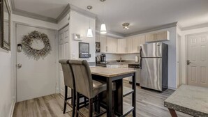 A modern kitchen with a wooden table and chairs, stainless steel appliances, and pendant lighting.
