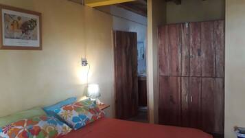 Un dormitorio con una cama, un armario de madera, una lámpara de pared y un cuadro enmarcado.