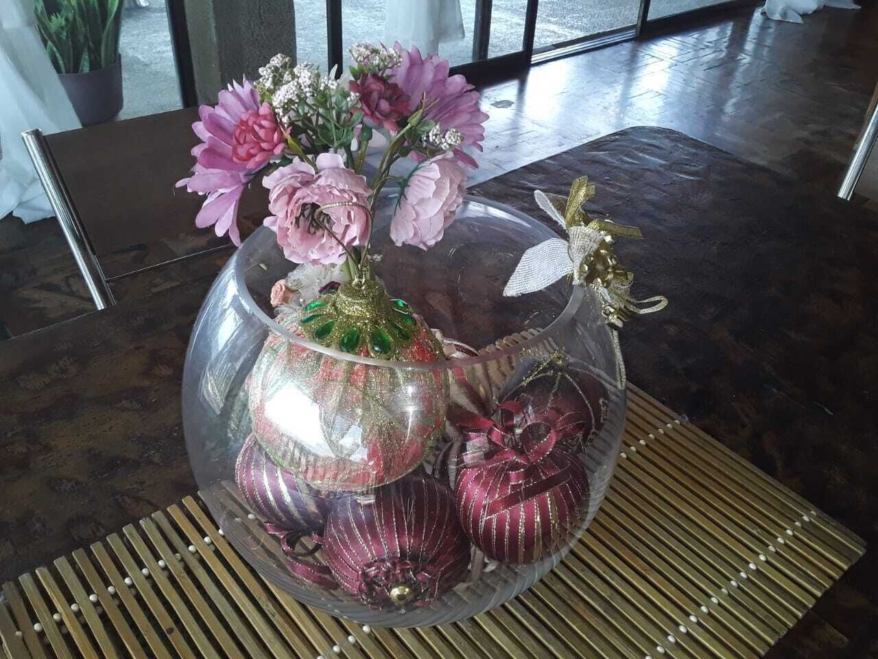 A table with a glass dome centerpiece containing pink flowers and decorative items.