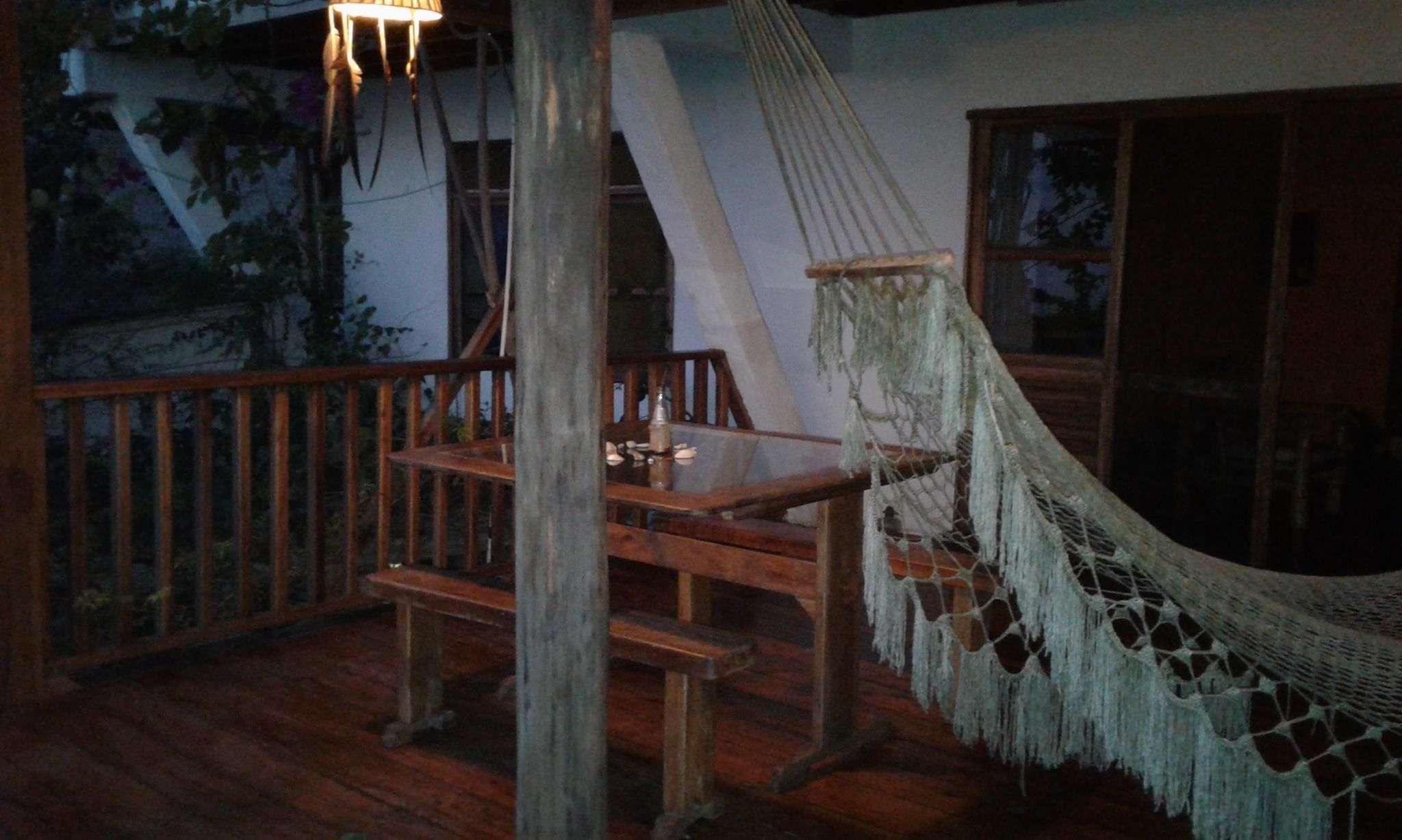 A wooden deck with a hammock, a table, and chairs.