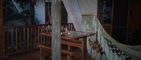 A wooden deck with a hammock, a table, and chairs.