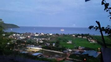 Uma cidade costeira ao entardecer, com vista para o mar e um navio ao longe.