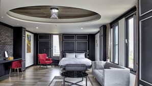 A modern bedroom with a large bed, a grey sofa, a red chair, and a black coffee table. - LaFika (Dongshan)