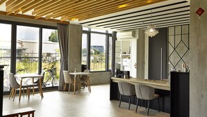 A modern dining area with a wooden ceiling, large windows, and a view of bicycles outside. - LaFika (Dongshan)