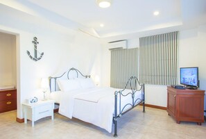 A bedroom with a bed, nightstand, TV, and a wooden cabinet. - Prompimarn Villa (Pranburi)