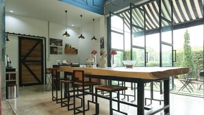 Una cocina moderna con una isla central, taburetes de bar, iluminación colgante y ventanas amplias que dan a vistas del exterior.
