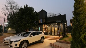 Un edificio moderno con fachada de vidrio y un coche estacionado frente a él.