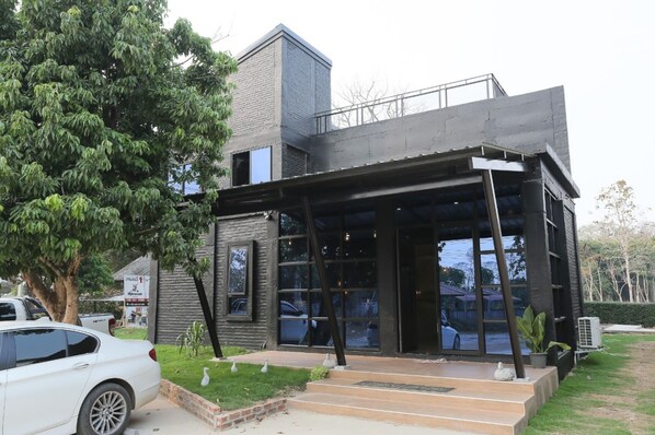 Un edificio moderno con entrada de vidrio, fachada de ladrillo y un coche estacionado adelante.