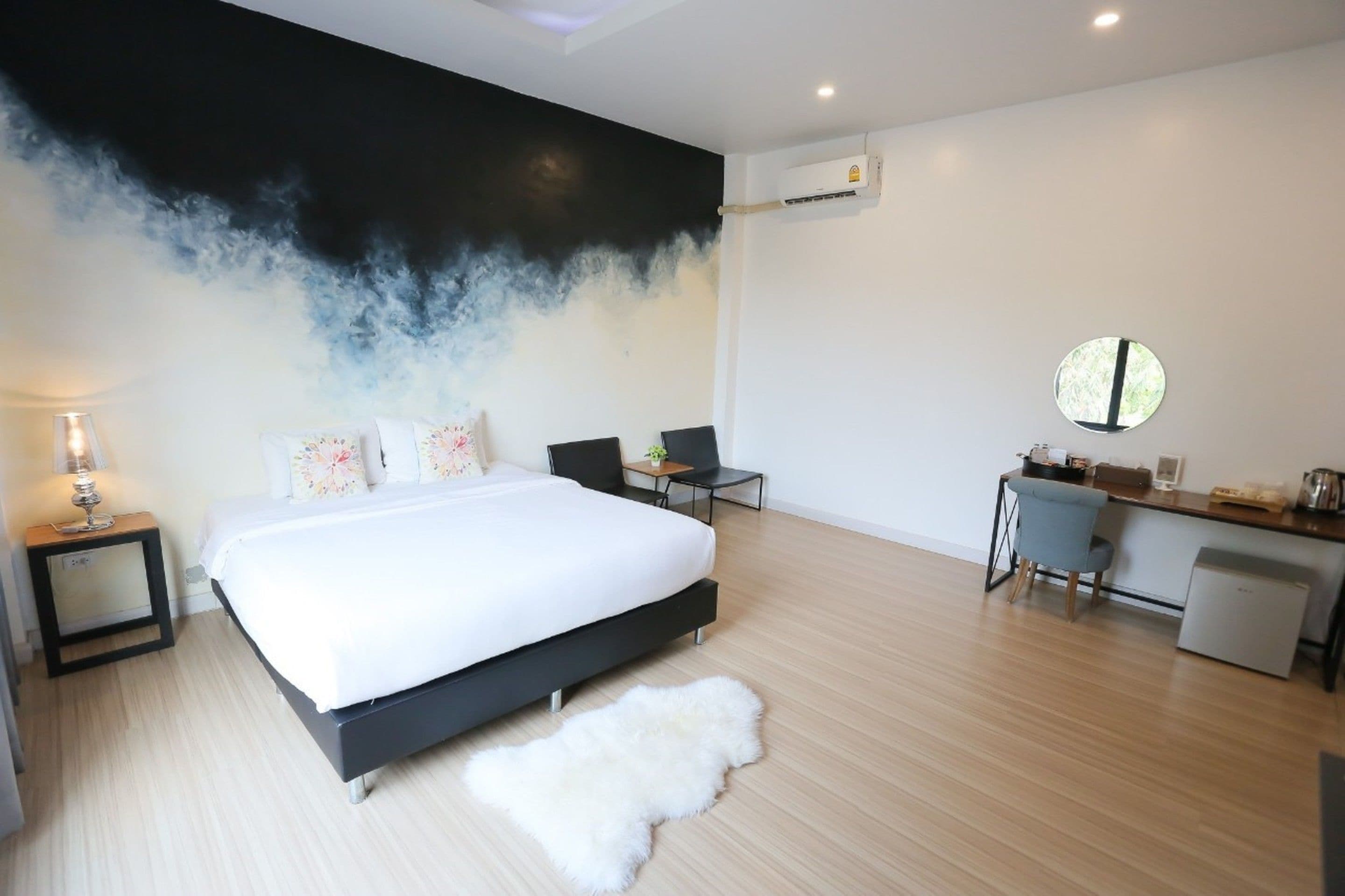 A modern bedroom with a large bed, a desk, and a chair.
