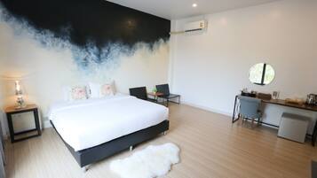 A modern bedroom with a large bed, a desk, and a chair.