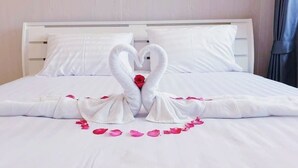Een bed met witte lakens en een handdoekopstelling in de vorm van een hart.