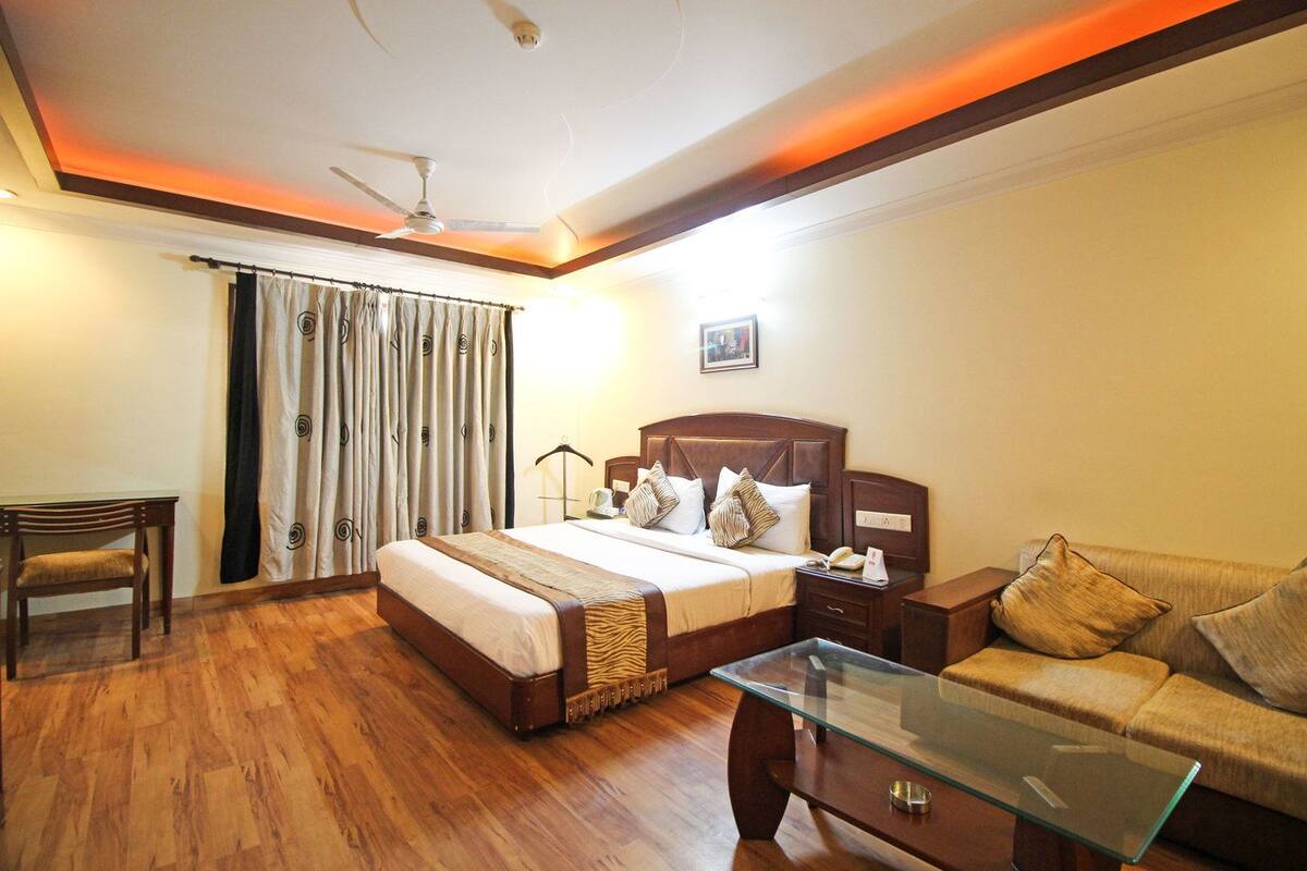 A hotel room with a bed, bedside table, lamp, and a glass coffee table.