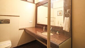 A bathroom with a marble sink, a toilet, a mirror, and a towel hanging on a ring. - Southview Apartment (New Delhi)