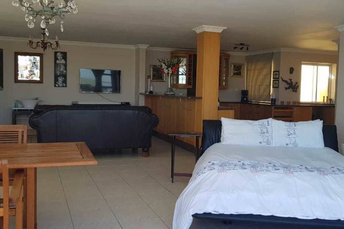 A hotel room with a bed, a dining table, a sofa, and a kitchen area.