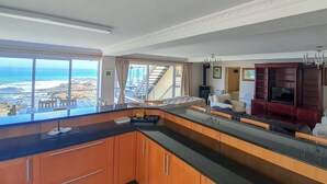 Une cuisine moderne avec vue sur l’océan, des armoires en bois et un grand îlot central.