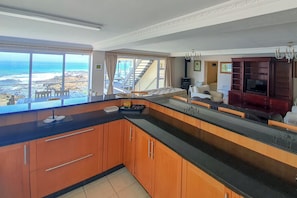 Cocina moderna con vista al océano, armarios de madera y una isla grande.