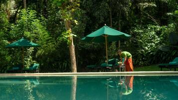 Una piscina al aire libre, sillones reclinables de piscina