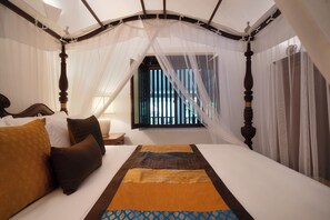 A four-poster bed with a canopy, a window with bars, and a bedside table with a lamp.