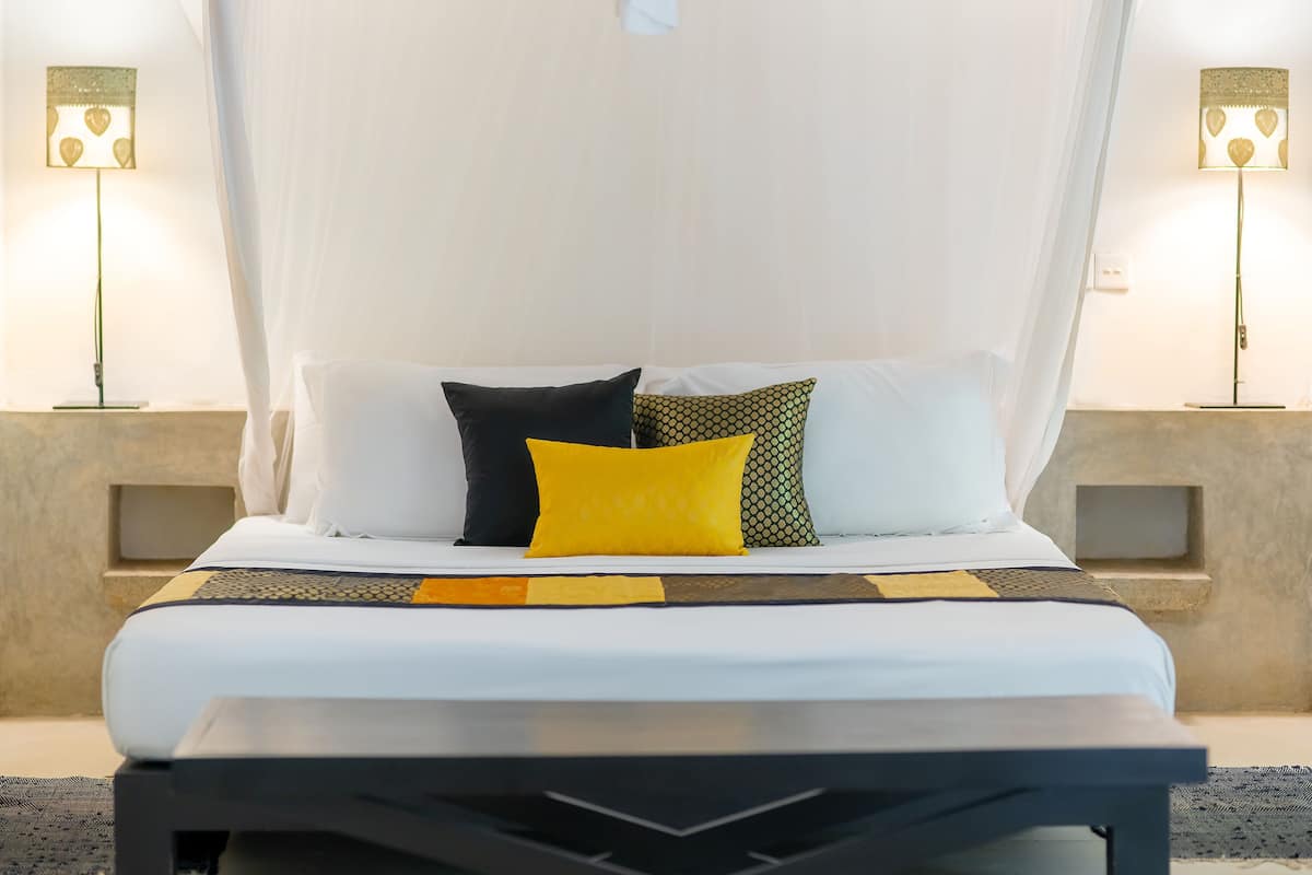 A bed with a canopy, two bedside lamps, and a bedside table.
