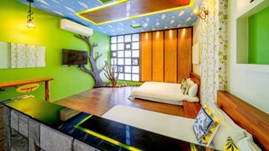 A modern room with a green wall, wooden paneling, a large window, a desk, and a bed with decorative pillows. - Cat Lazy B&B (Luodong)