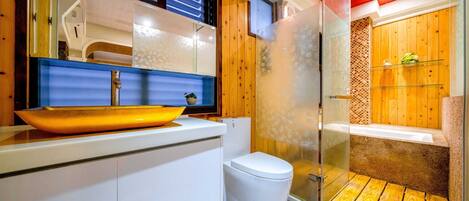 A modern bathroom with a glass-enclosed shower, a white toilet, and a wooden vanity.