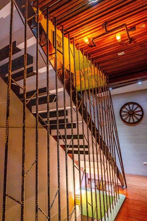 A staircase with a unique chain railing design, a wooden ceiling, and a decorative wheel on the wall. - Cat Lazy B&B (Luodong)