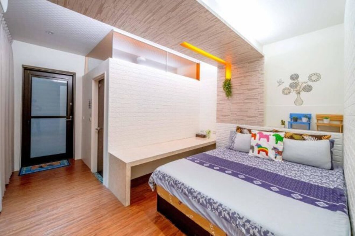 A bedroom with a bed, a bedside table, a window, and a door.