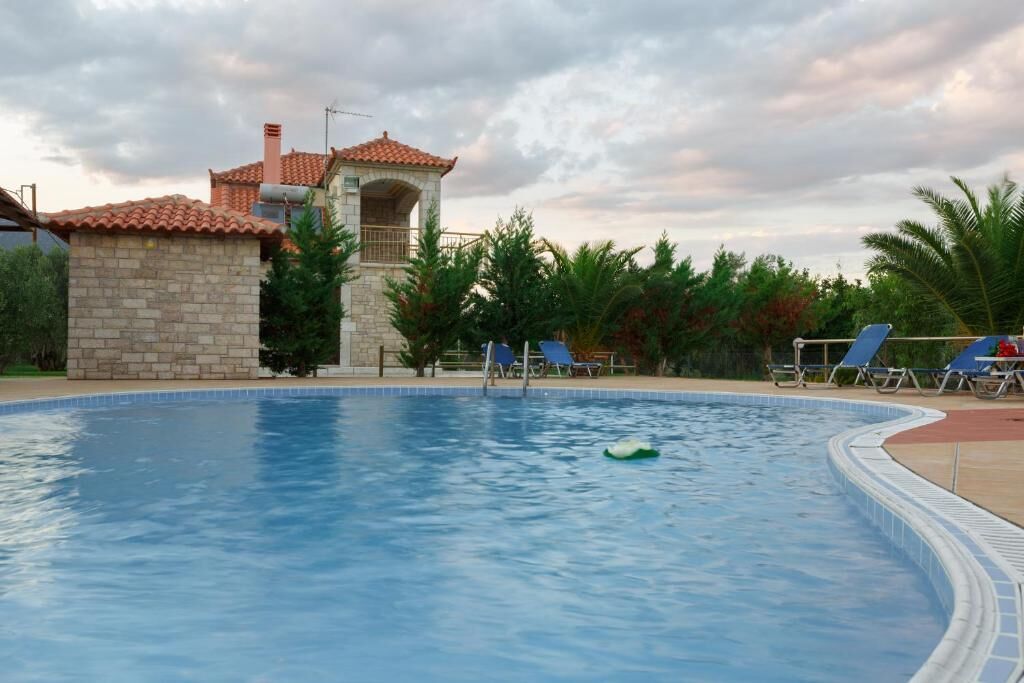 A swimming pool with lounge chairs, a stone structure, and a palm tree in the background.
