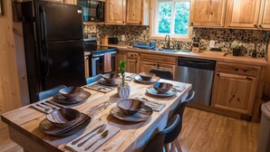 A modern kitchen with wooden cabinets, a black refrigerator, a microwave, a stove, and a sink.