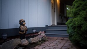 A bear-shaped welcome sign outside a house with steps leading to a door.