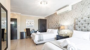 A hotel room with two beds, a desk, a chair, and a large mirror.