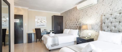 A hotel room with two beds, a desk, a chair, and a large mirror.