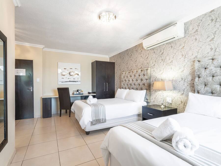 Une chambre d’hôtel avec deux lits, un bureau, une chaise et un grand miroir.