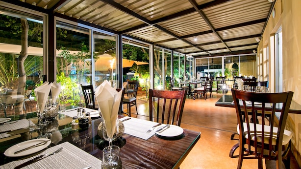 A dining area with glass tables, wooden chairs, and a view of the outdoors.