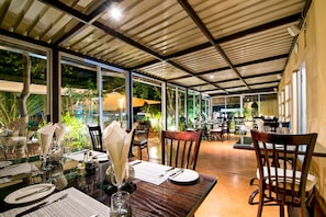 A dining area with glass tables, wooden chairs, and a view of the outdoors. - Auas City Hotel (Windhoek)