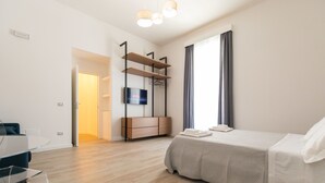 Een moderne slaapkamer met een bed, een aan de muur bevestigde televisie, een houten dressoir en een bureau met een stoel.