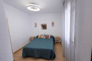 Une chambre à coucher comprenant un lit, deux tables de chevet, un luminaire au plafond et des œuvres d’art murales.