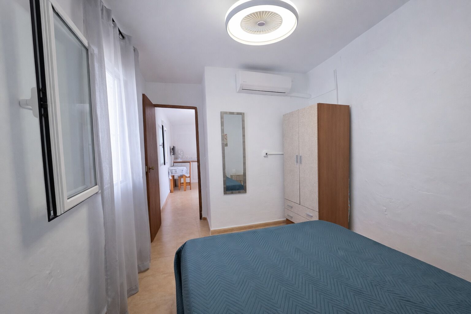 Een slaapkamer met een bed, een kledingkast, een airconditioning en een deur naar een badkamer.