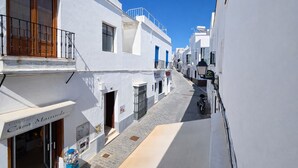 A narrow street with white buildings, a motorcycle parked on the side, and a sign for 'Casa Manuel.'
