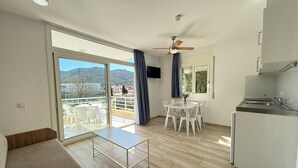 A modern kitchen with a built-in oven, a dining area with a table and chairs, a ceiling fan, and a view of the outdoors through a sliding glass door. - Agi Rescator 212 Apartamento for rent in Roses Girona. (Rosas / Roses)