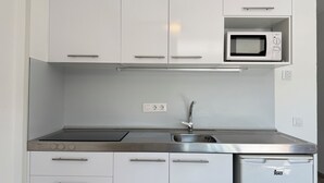 A modern kitchen with white cabinets, a stainless steel sink, a microwave, and a dishwasher. - Agi Rescator 212 Apartamento for rent in Roses Girona. (Rosas / Roses)