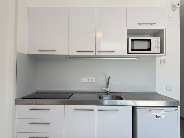 A modern kitchen with white cabinets, a stainless steel sink, a microwave, and a dishwasher.