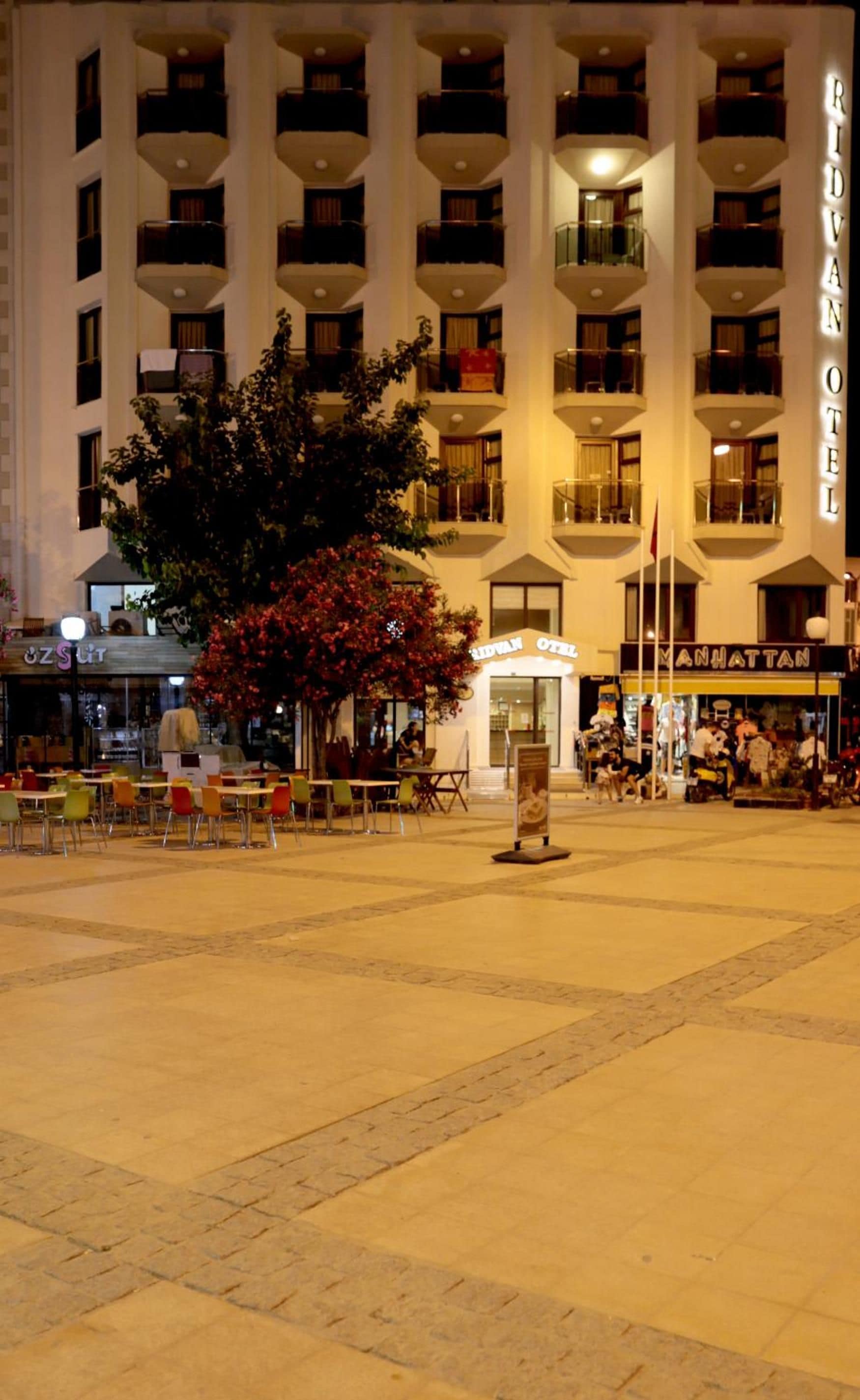Um hotel com vários andares, área de estar ao ar livre e uma grande árvore no centro.