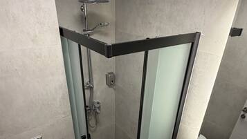 A modern bathroom with a glass-enclosed shower, a toilet, and a sink with a marble countertop.