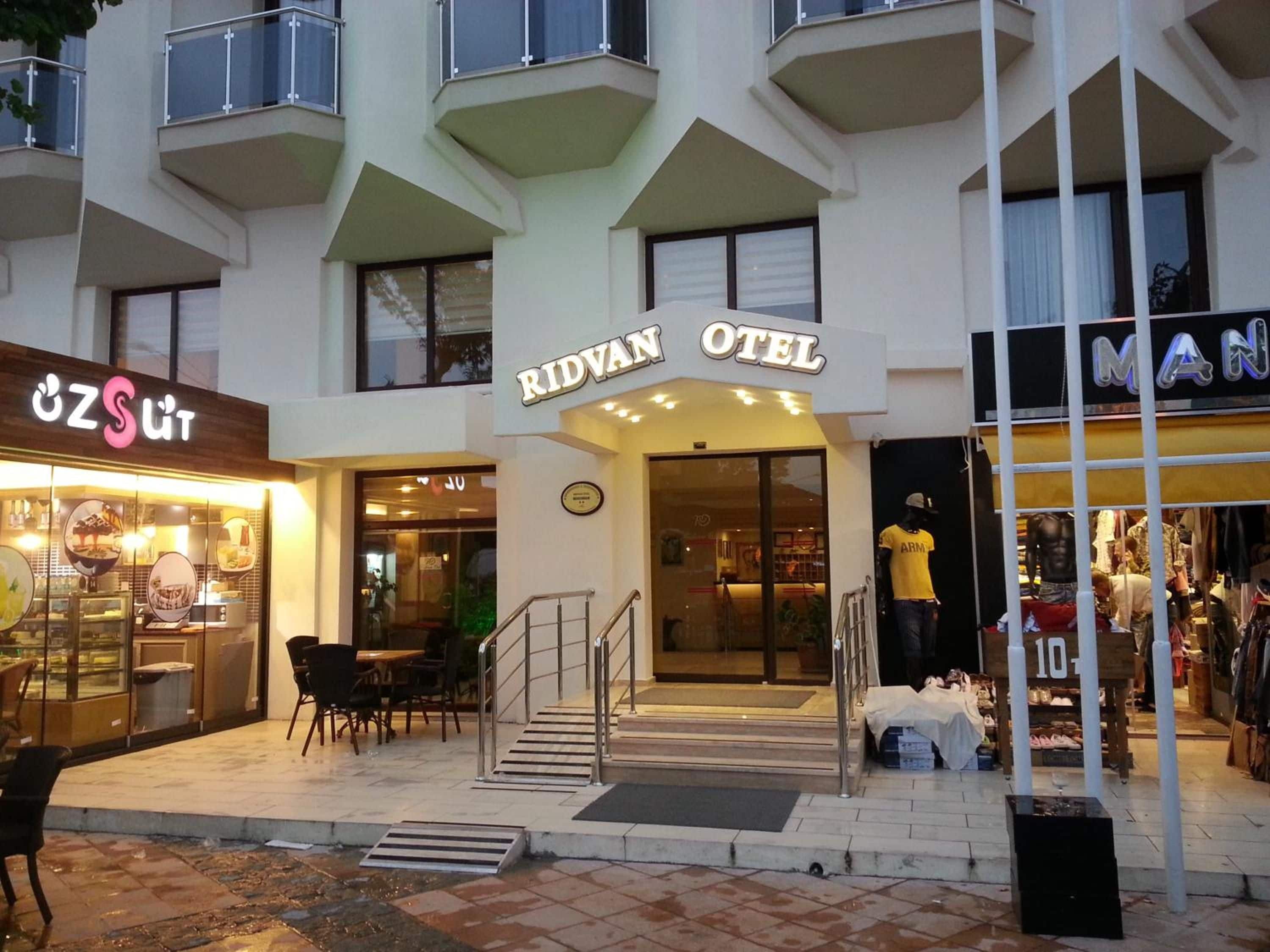 Een hotelingang met een bord waarop 'RIDVAN OTEL' staat en een etalage met een bord 'MAN'.